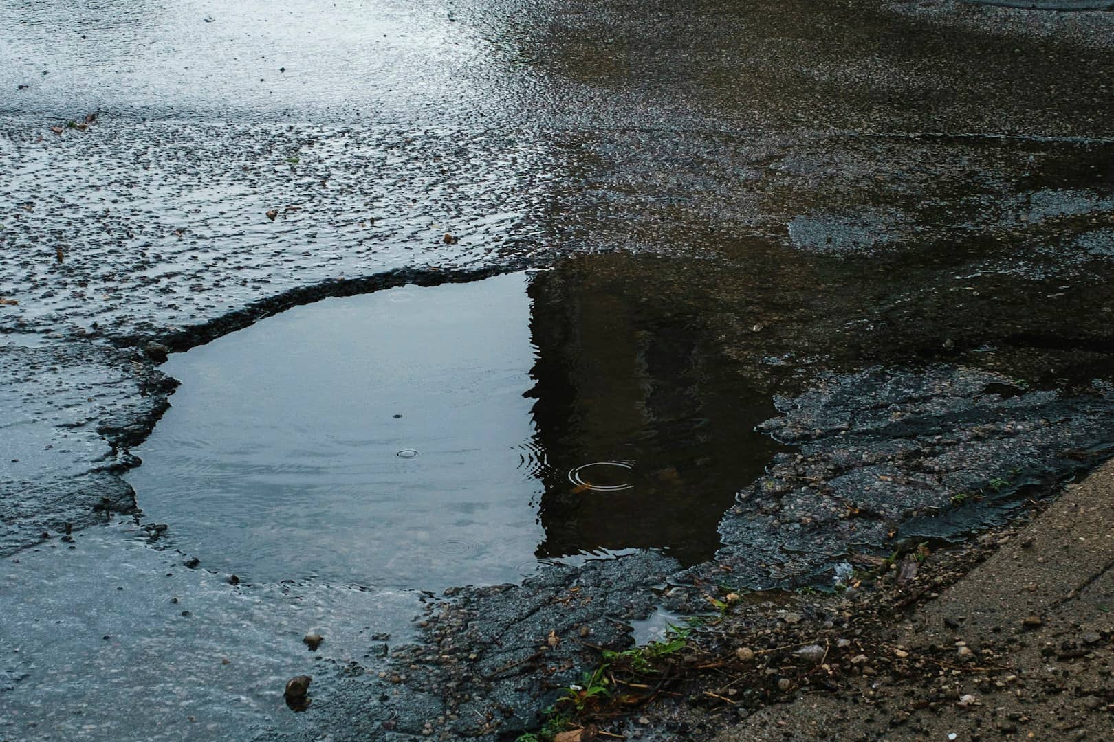 Mit Wasser gefülltes Schlagloch in einer Asphaltdecke